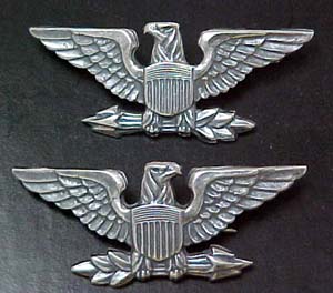 The image shows two US Army Colonels' ranks insignia. Insignia consists of an eagle facing to his right, clutching a bundle of arrows.     